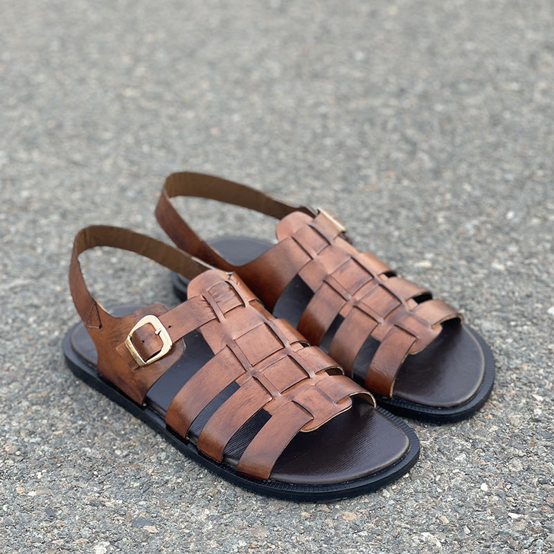 Handmade brown leather strap sandals for men on a grey textured surface