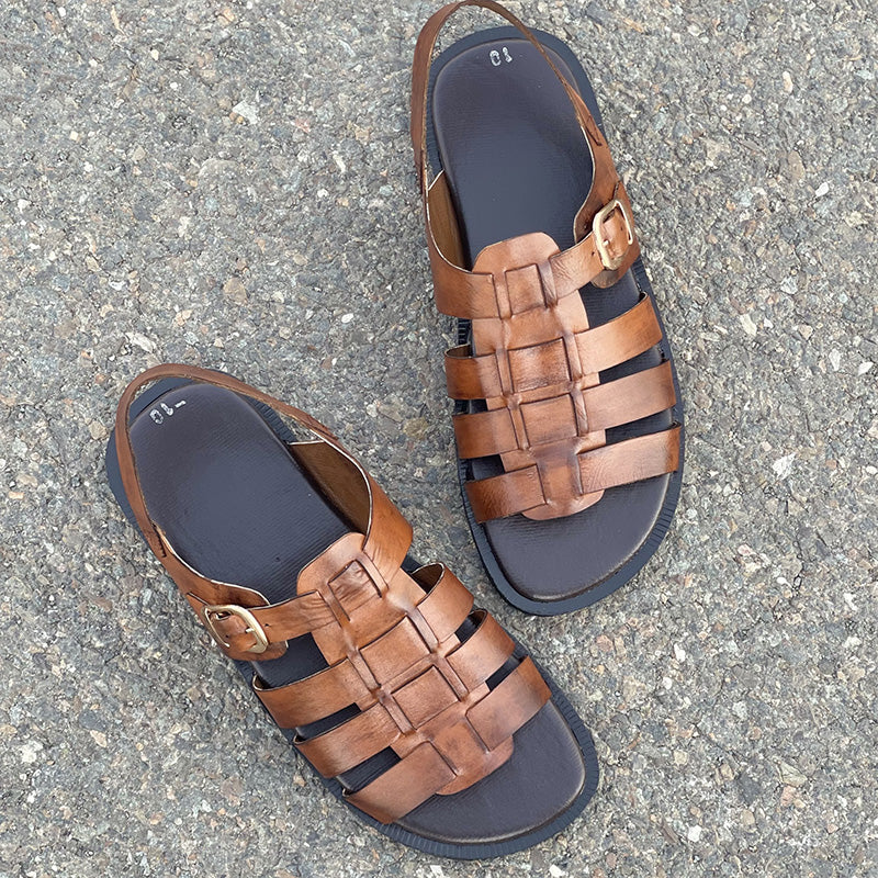 Handmade brown leather strappy sandals for men on a grey textured background