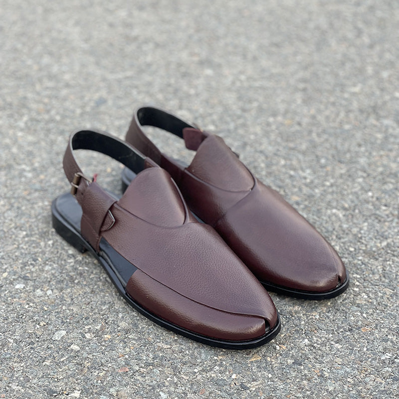Pair of handmade brown leather men's mules with slingback straps on a grey surface