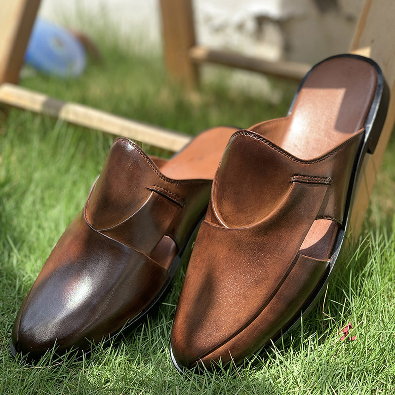 Pair of handmade brown leather mules for men on green grass