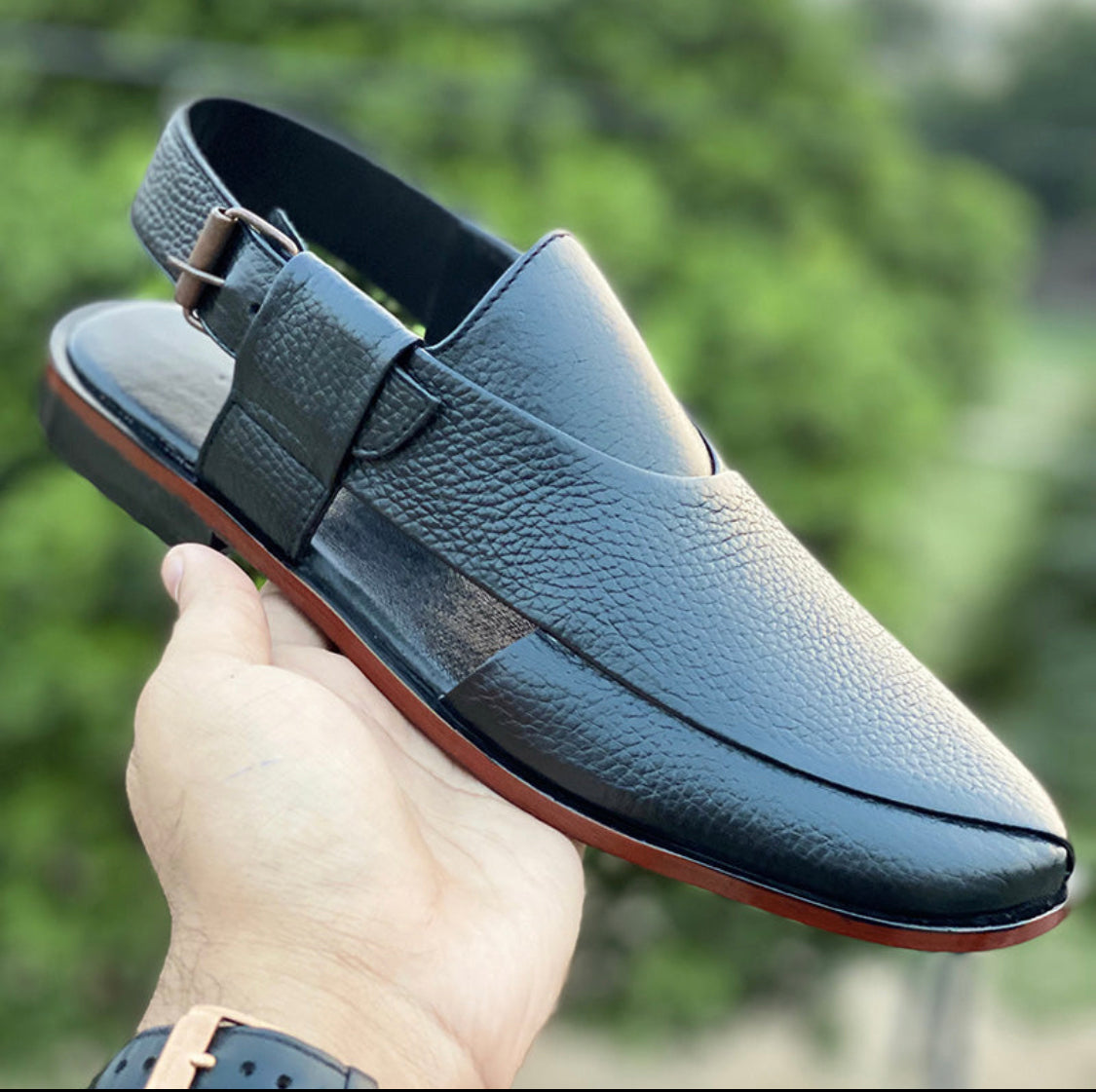Handmade black leather men's mules with a buckle strap and textured finish.