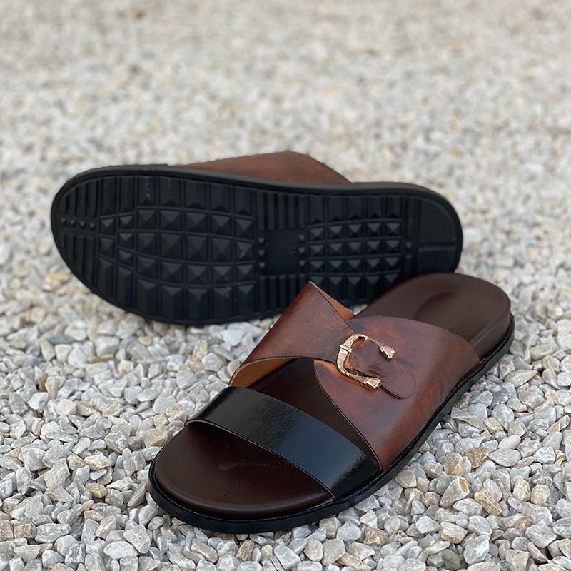 Brown leather handmade men's sandals with a gold buckle on a pebble background