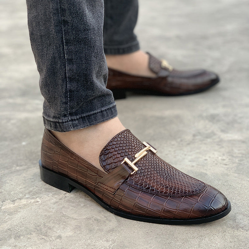Close-up of men's brown crocodile texture leather loafers with a gold buckle detail