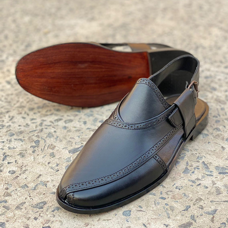 Handmade black leather men's mules with decorative brogue detailing and brown soles.