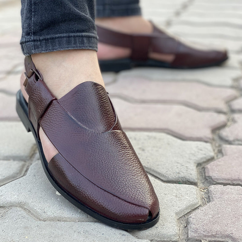 Close-up of men's handmade brown leather mule shoes on a paved surface