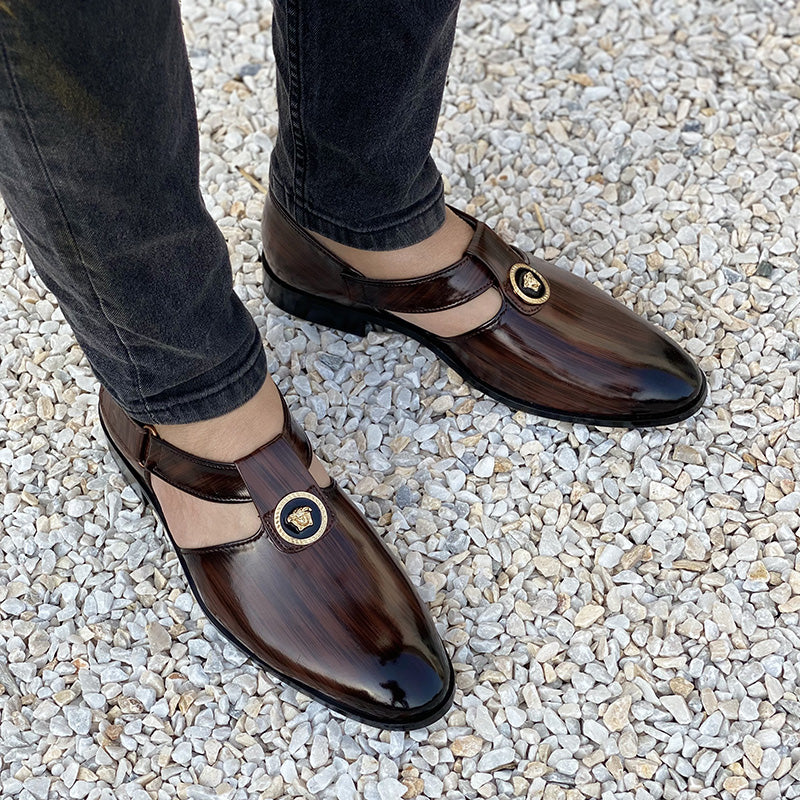 Handmade men's brown formal loafers with gold buckle detail on a gravel surface