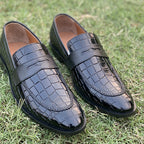 Black crocodile embossed leather loafers for men on green grass