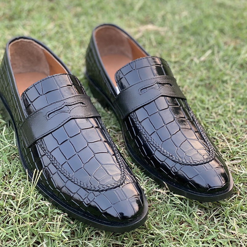 Black crocodile embossed leather loafers for men on green grass