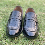 Black crocodile pattern leather loafers for men on green grass