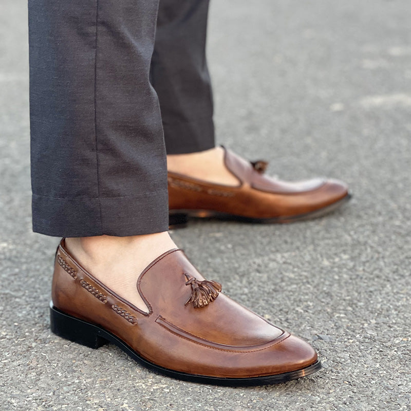 Man wearing brown handmade leather tassel loafers with grey formal trousers