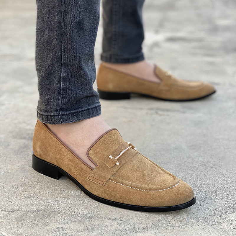 Man wearing tan suede loafers with gold metal hardware and grey jeans