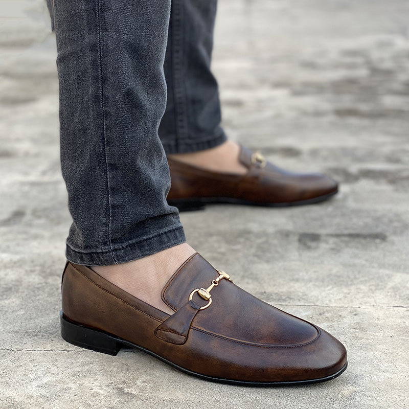 Man wearing brown handmade leather bit loafers with gold hardware and grey denim jeans