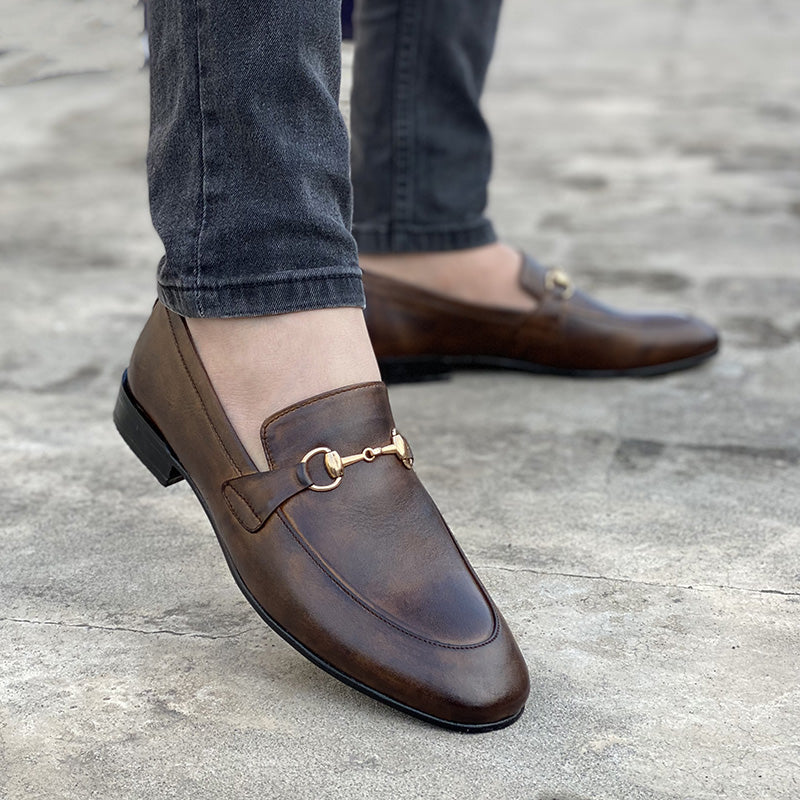 Men's brown leather horsebit loafers worn with grey jeans