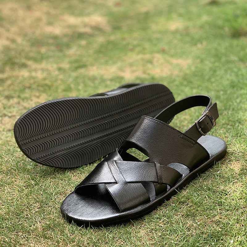 Pair of black handmade leather sandals for men on green grass