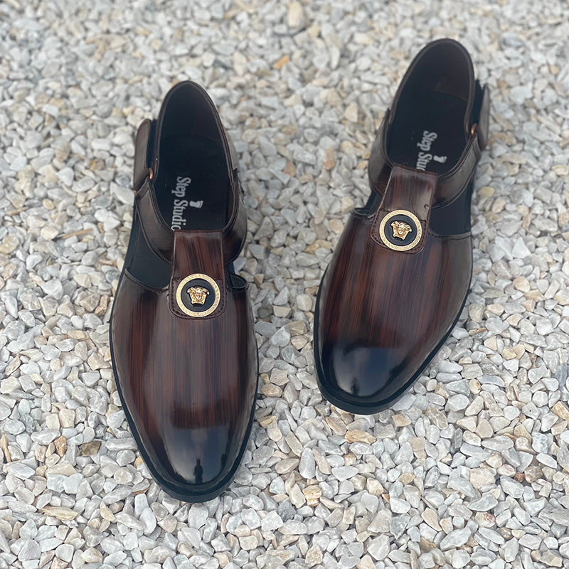 Men's brown handmade formal loafers with gold buckle detail on a white pebble background
